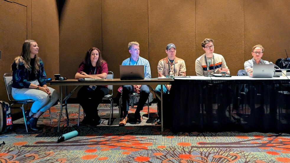 Six user group members sitting at a table during a panel at the MN GIS/LIS Consortium's annual conference.